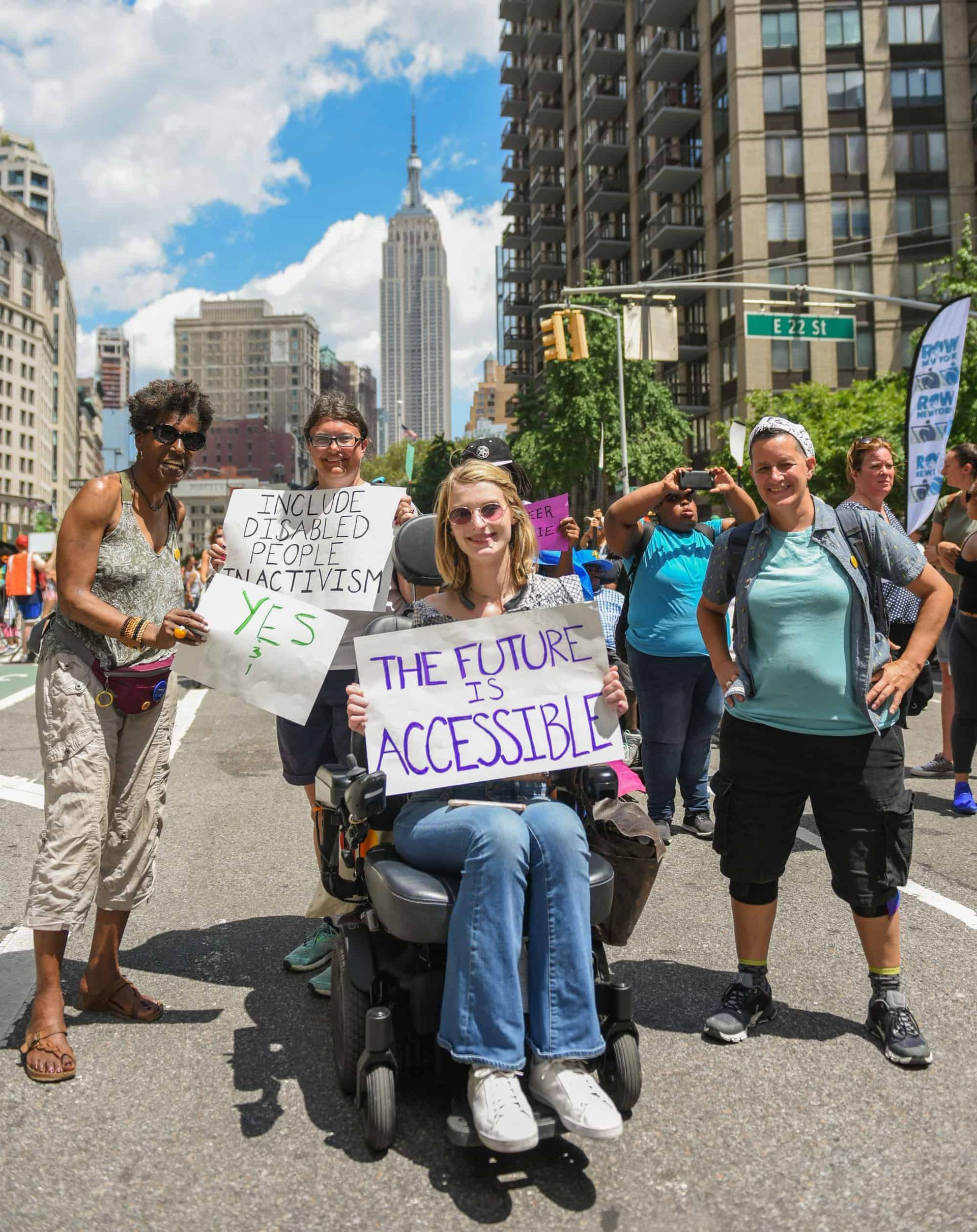 People protesting in NYC street, woman in wheelchair holding 