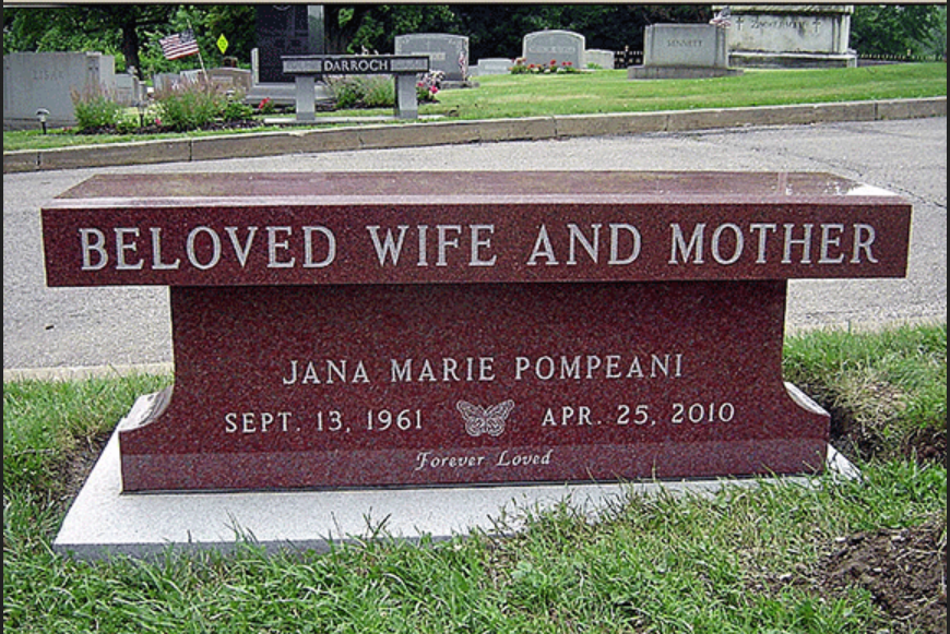 A red bench in a cemetery that says beloved wife and mother