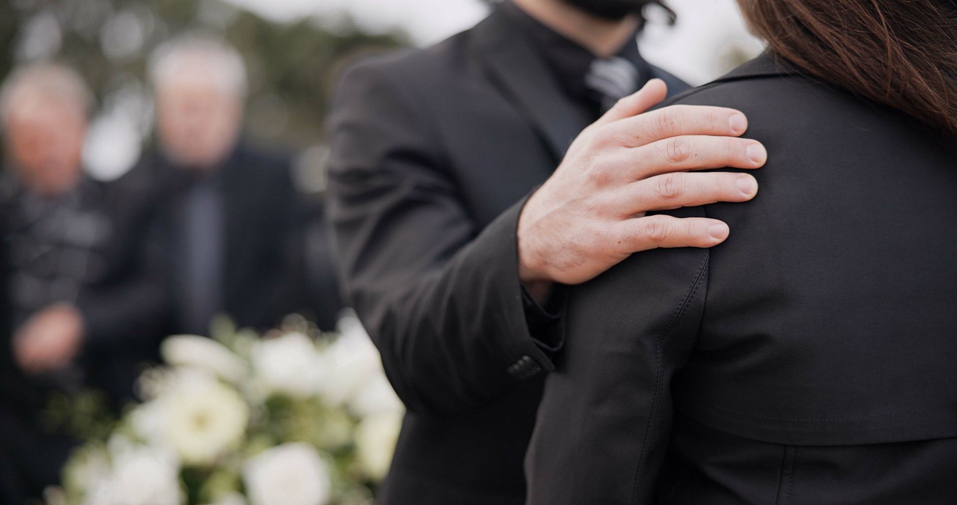 A man is hugging a woman at a funeral.