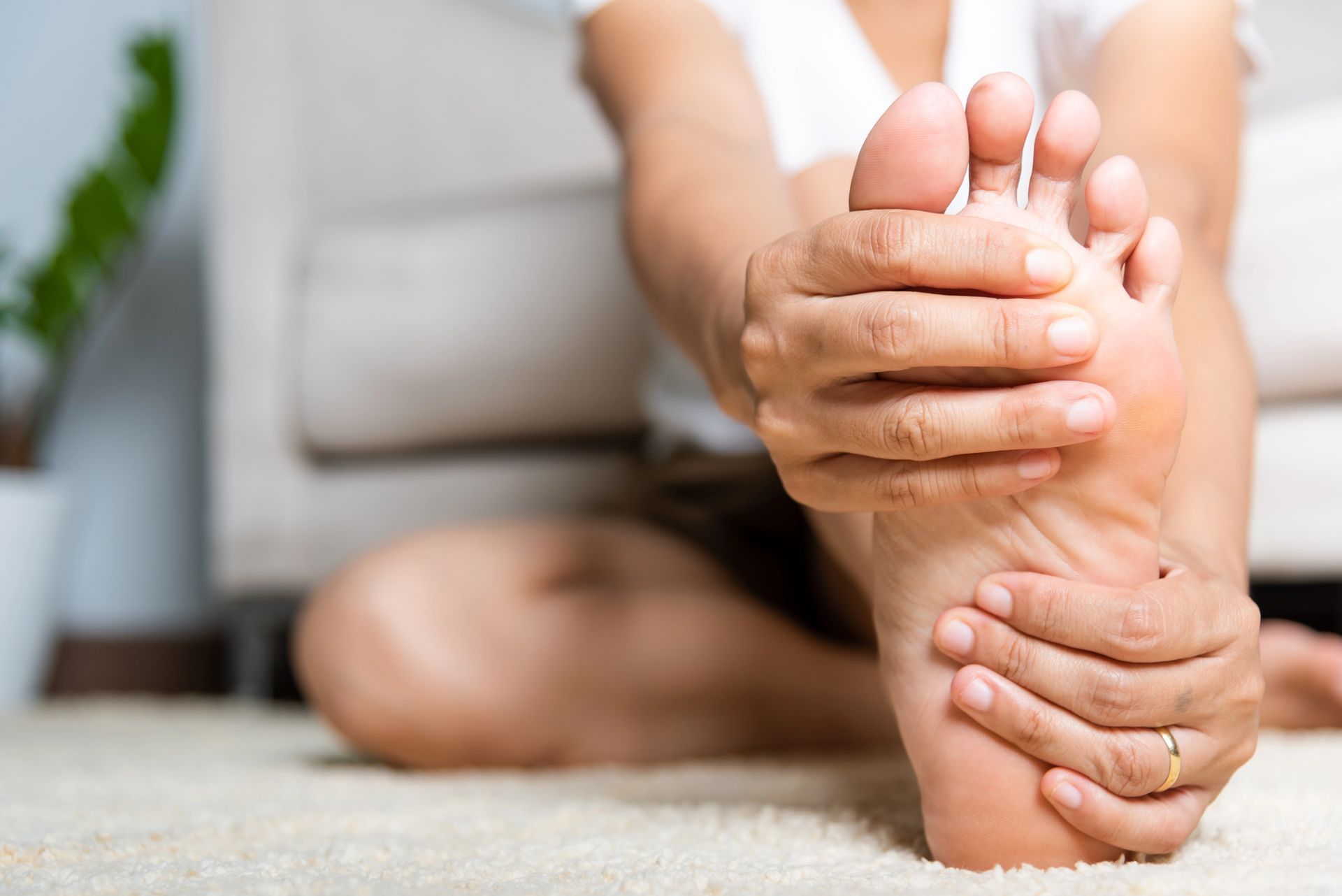 Person massaging the sole of a bare foot while sitting on a couch
