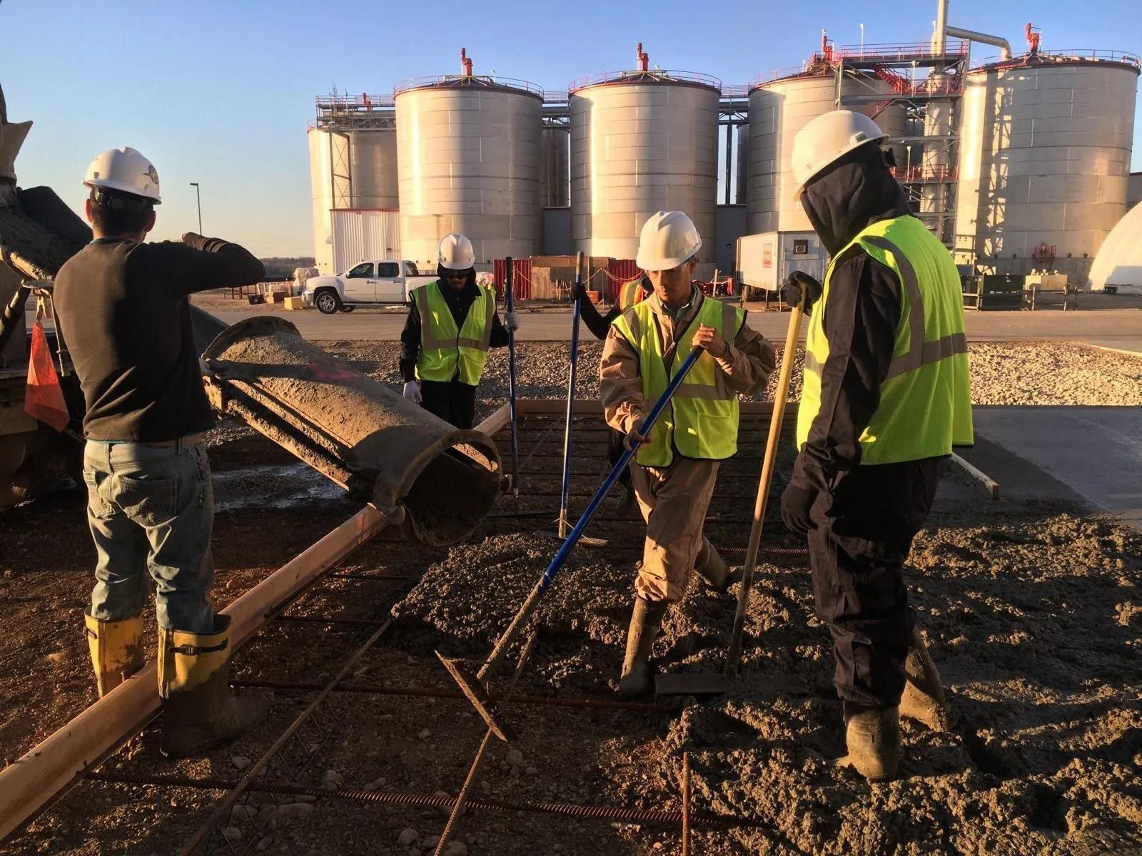 A group of construction workers wearing hard hats and safety vests