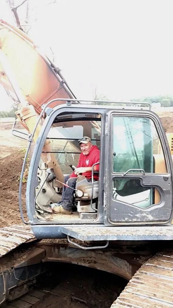 A man is sitting in the driver 's seat of an excavator.