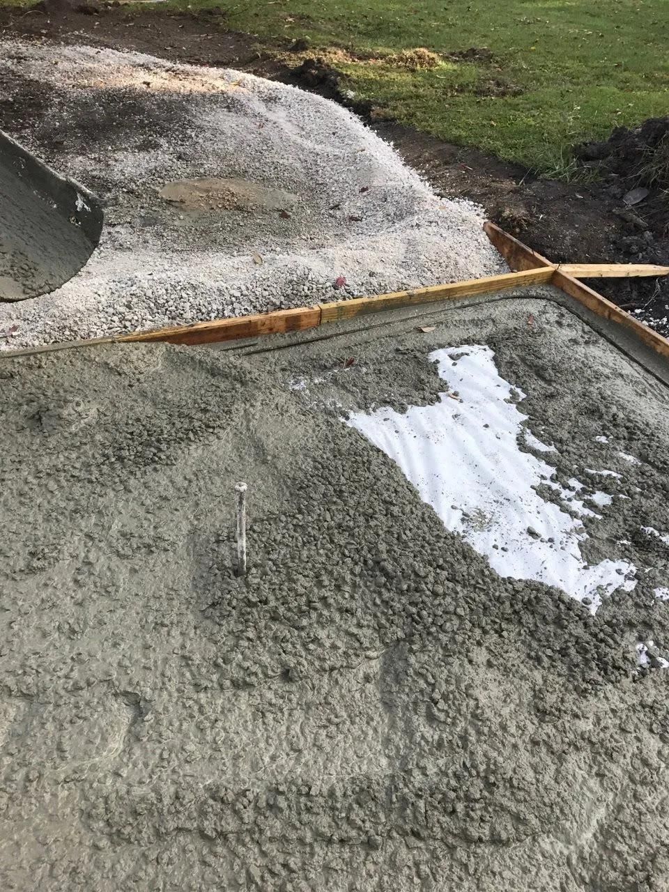 A pile of concrete is being poured into a concrete slab.
