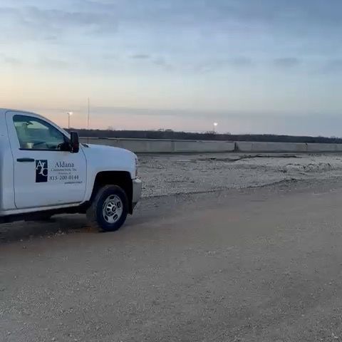 A white truck is parked on a dirt road.