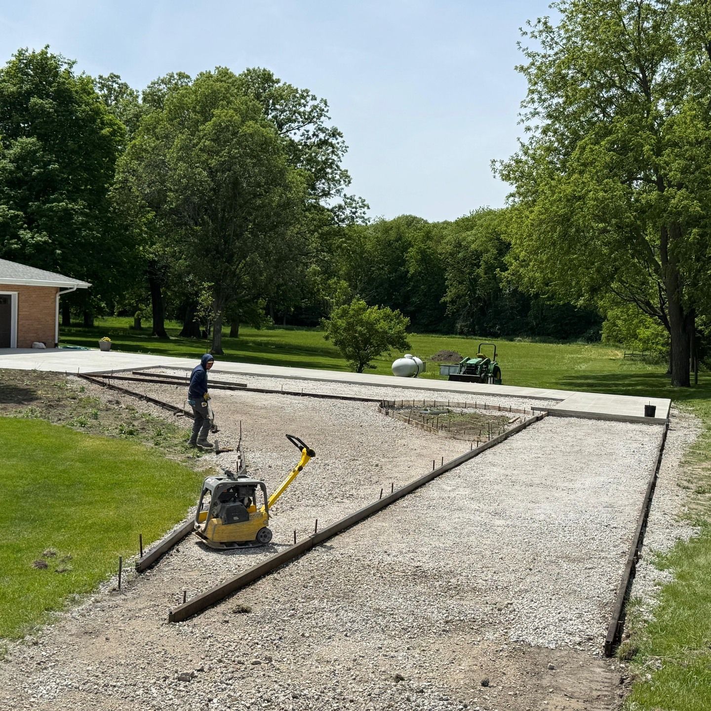 A concrete driveway is being built in a yard