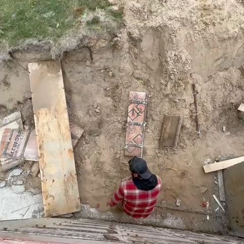 A man in a plaid shirt is sitting in the dirt.