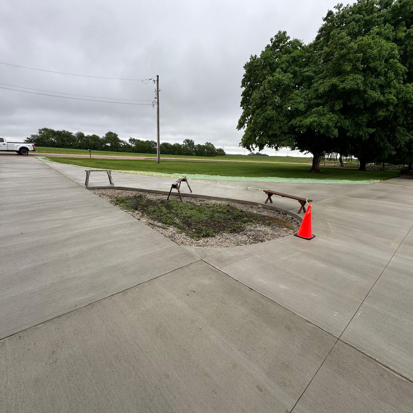 A concrete driveway with a bench and an orange cone