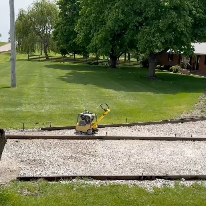 A yellow and black machine is sitting on top of a gravel road.