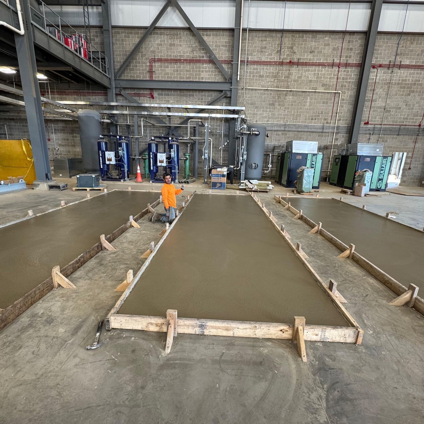 A man in an orange shirt is standing on a concrete floor