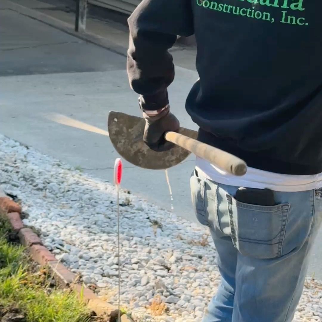 A man wearing a construction inc. sweatshirt is holding a shovel