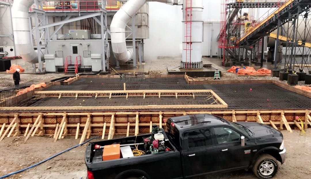 A black truck is parked in front of a building under construction.