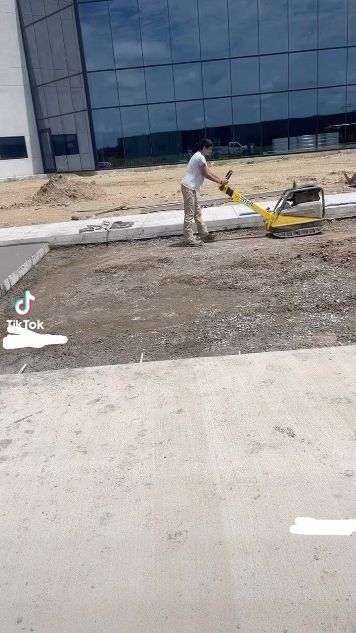 A man is working on a sidewalk in front of a building.