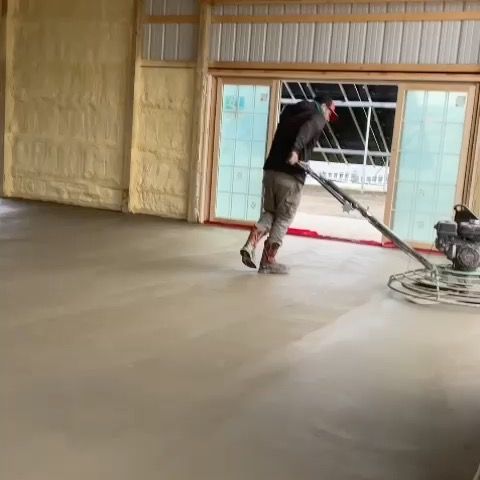 A man is using a vacuum cleaner to clean a concrete floor.