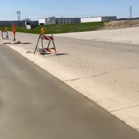 A concrete road with orange and white barriers on the side of it.