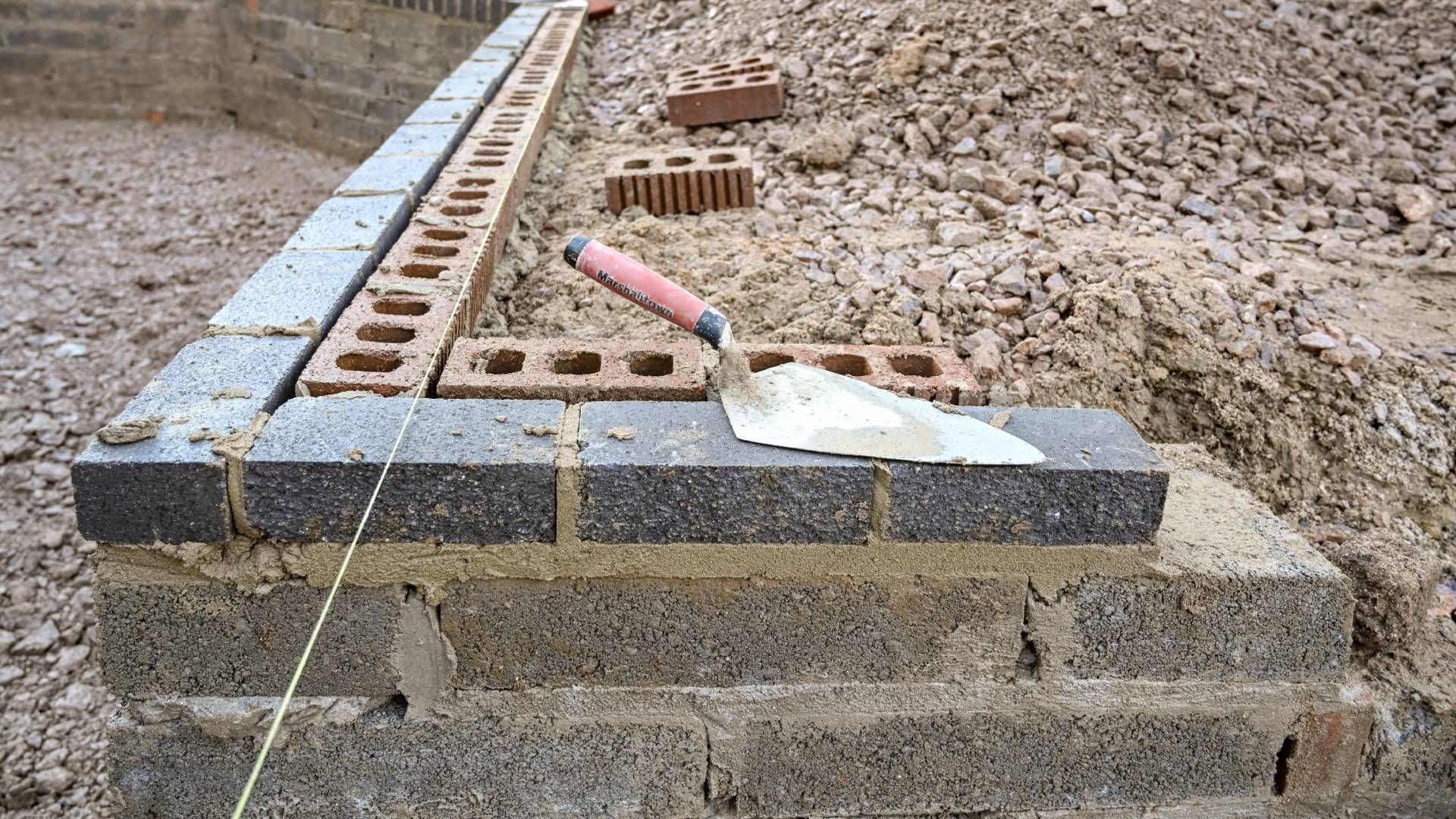 A trowel is sitting on top of a brick wall.