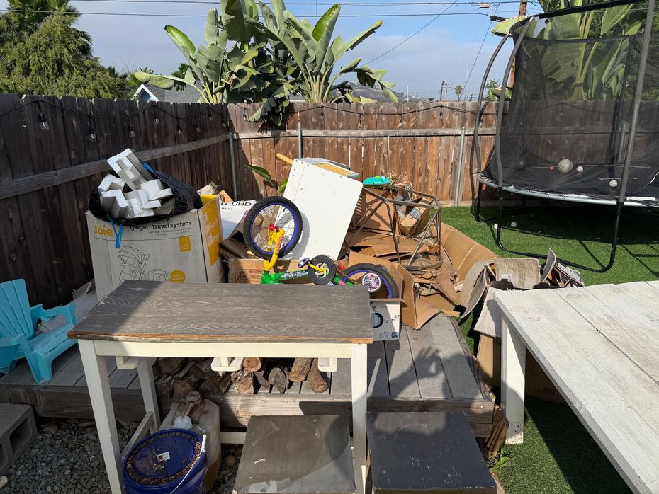 Pile of wooden planks on grass next to a brick border.