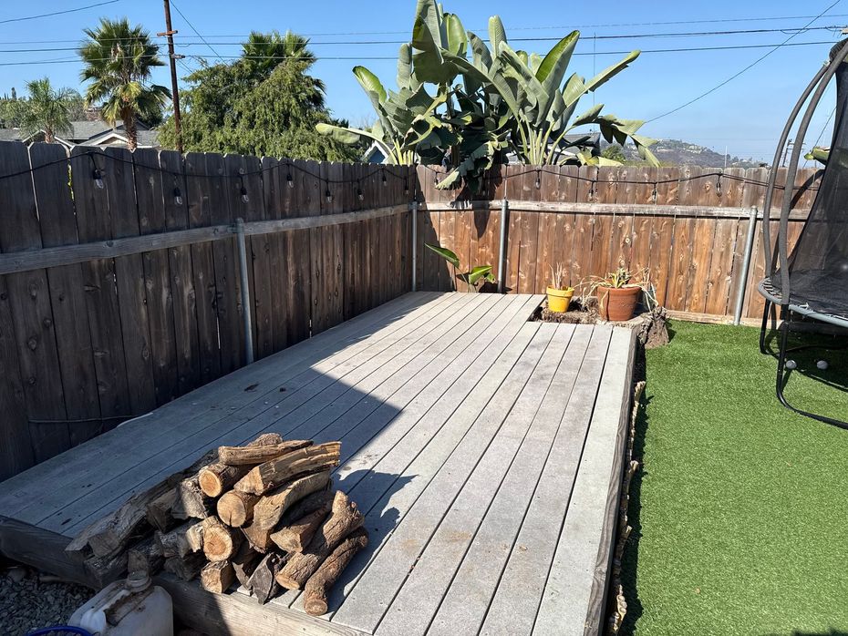 Pile of assorted weathered wooden planks, a ladder, and a frame; outdoor setting.