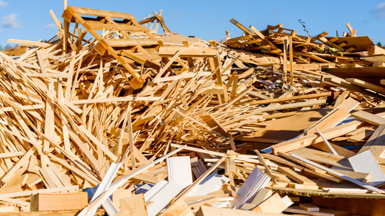 Pile of wood debris under a blue sky, likely from a demolition or construction site.