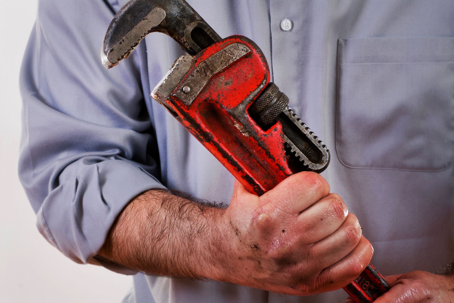 Close-up of plumber holding tool, showcasing plumbing services ready for repair work.