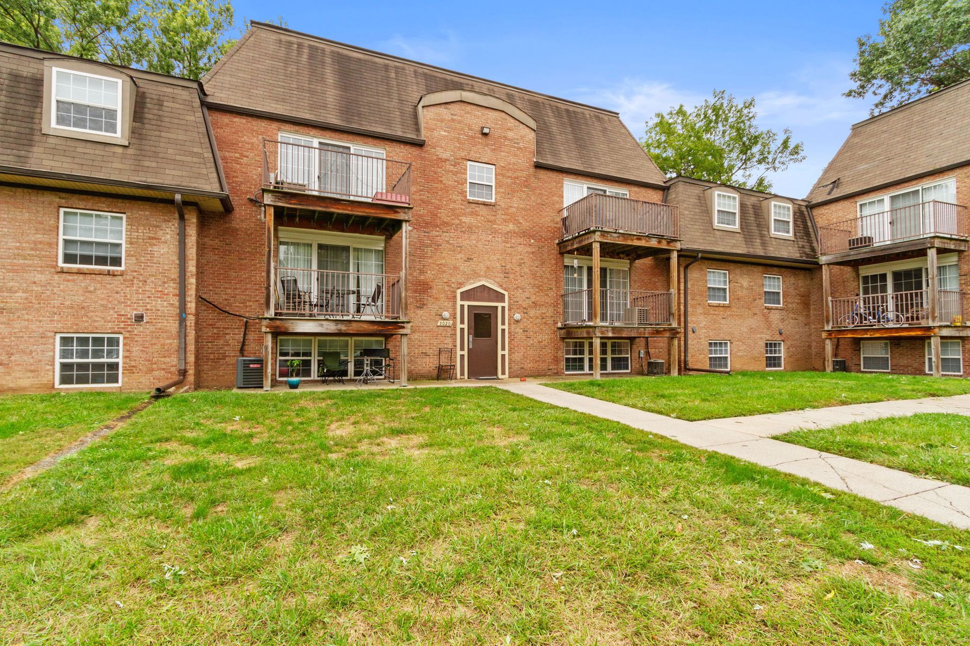 Brick apartment buildings with balconies and green lawn.