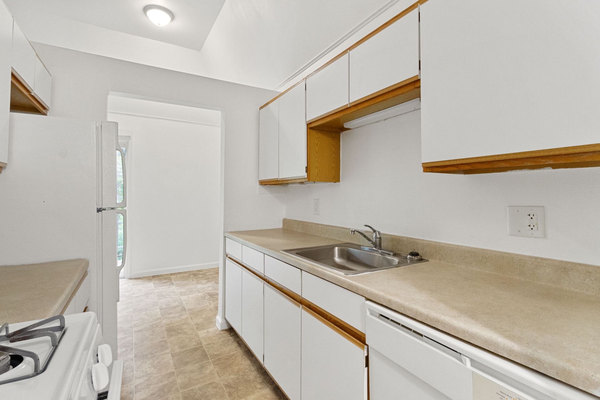 White kitchen with cabinets, sink, and appliances.