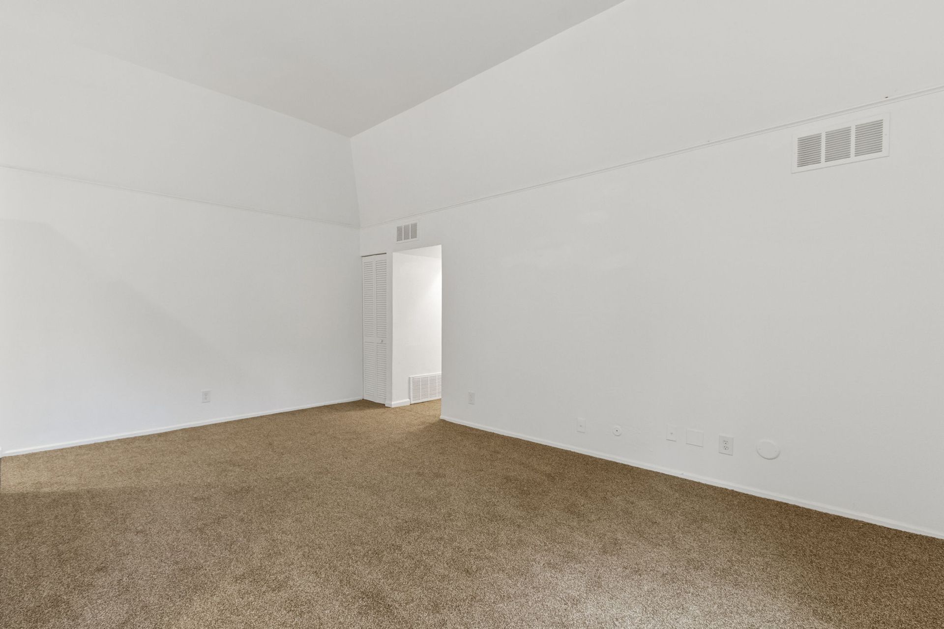 Empty room with beige carpet, white walls, and a doorway.