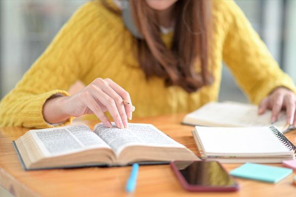 A woman is sitting at a table reading a book.