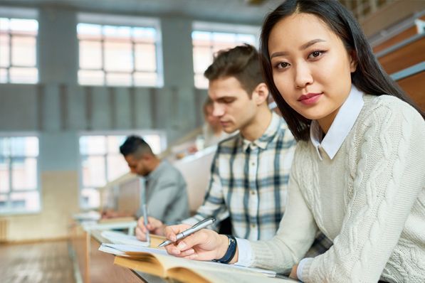 A group of students are sitting at desks in a lecture hall.