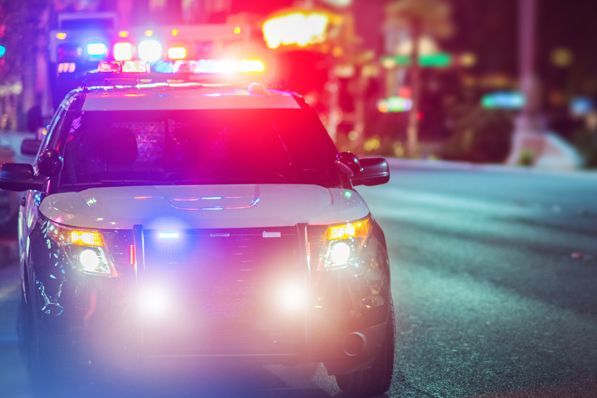 A police car is driving down a city street at night.