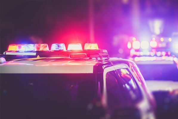 A police car with red and purple lights on top of it at night.
