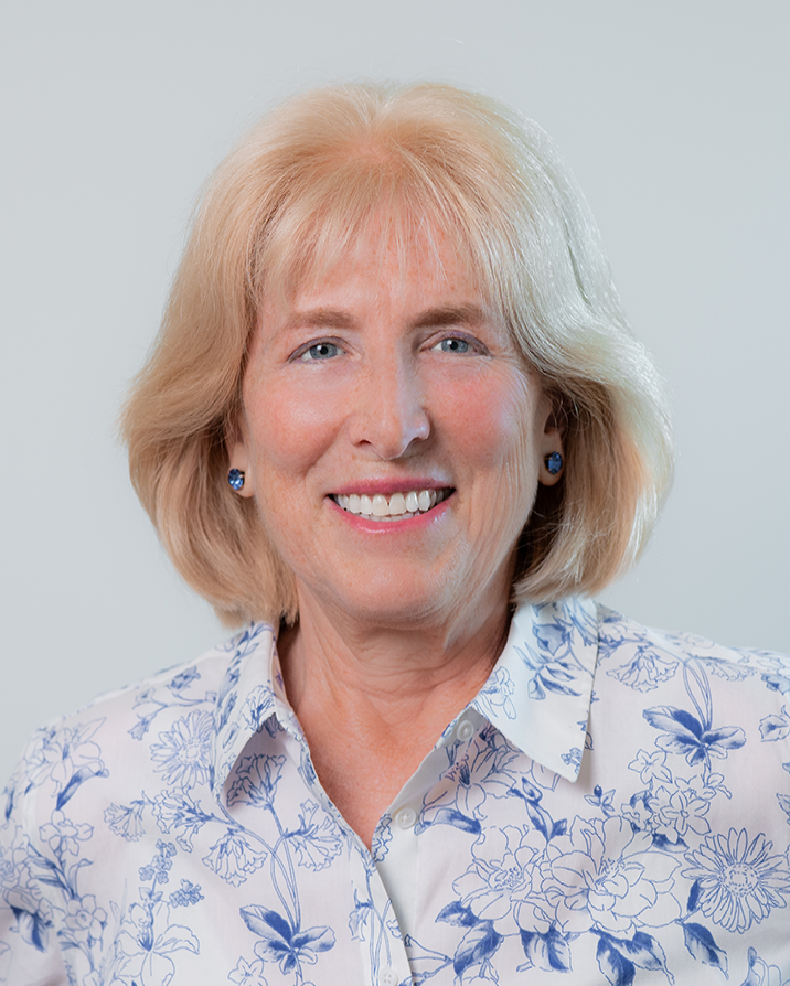 A woman with blonde hair and blue eyes is smiling for the camera