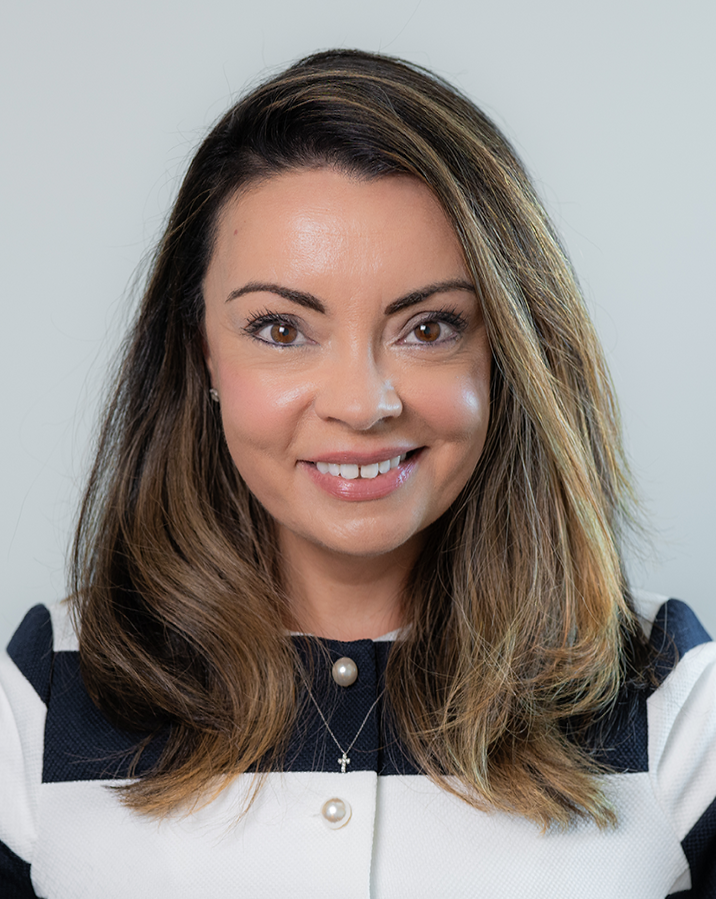 The woman is wearing a pink shirt and smiling for the camera.