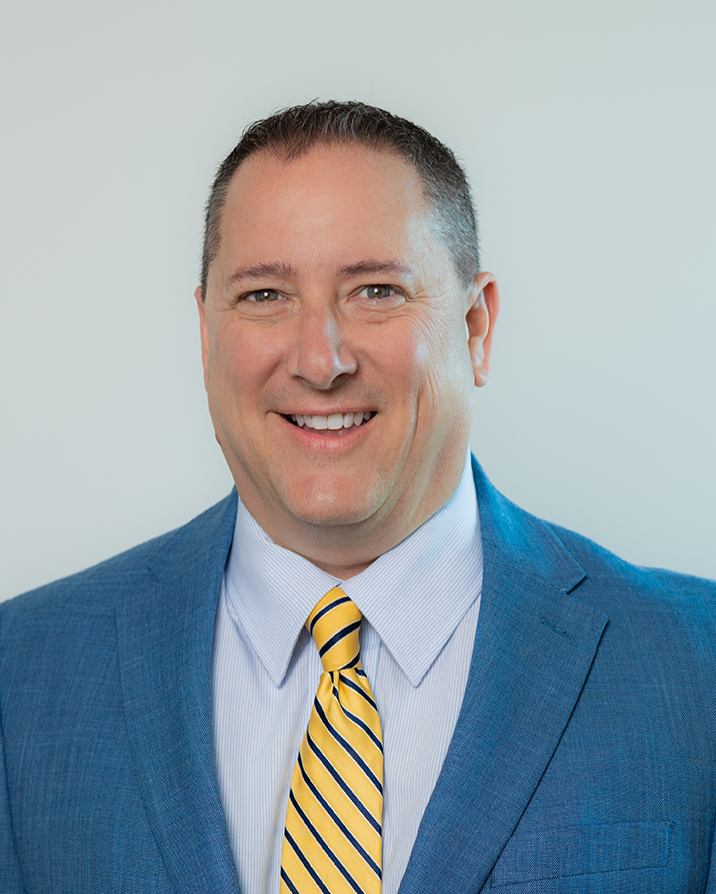 A man in a suit and tie is smiling for the camera