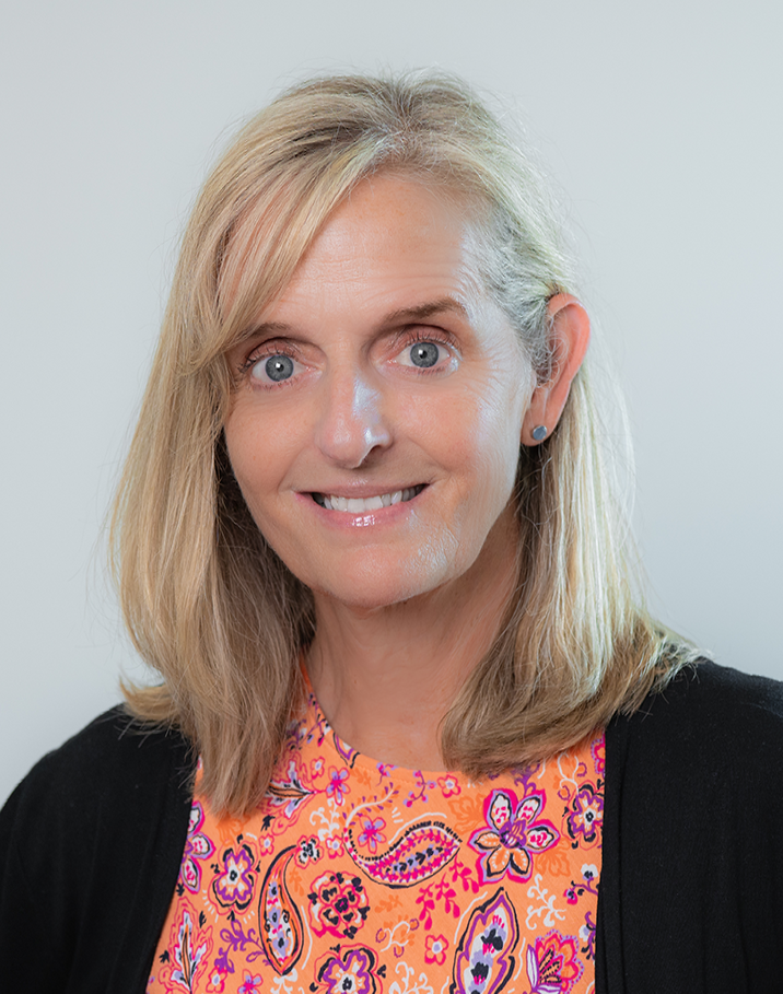 The woman is wearing a pink shirt and smiling for the camera.