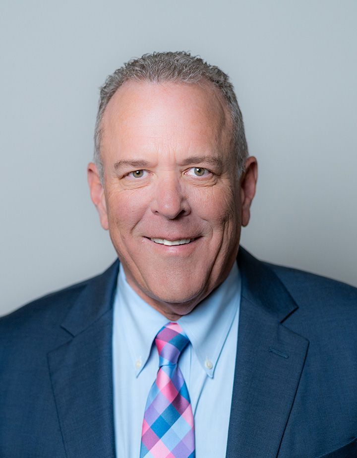 A man in a suit and tie is smiling for the camera
