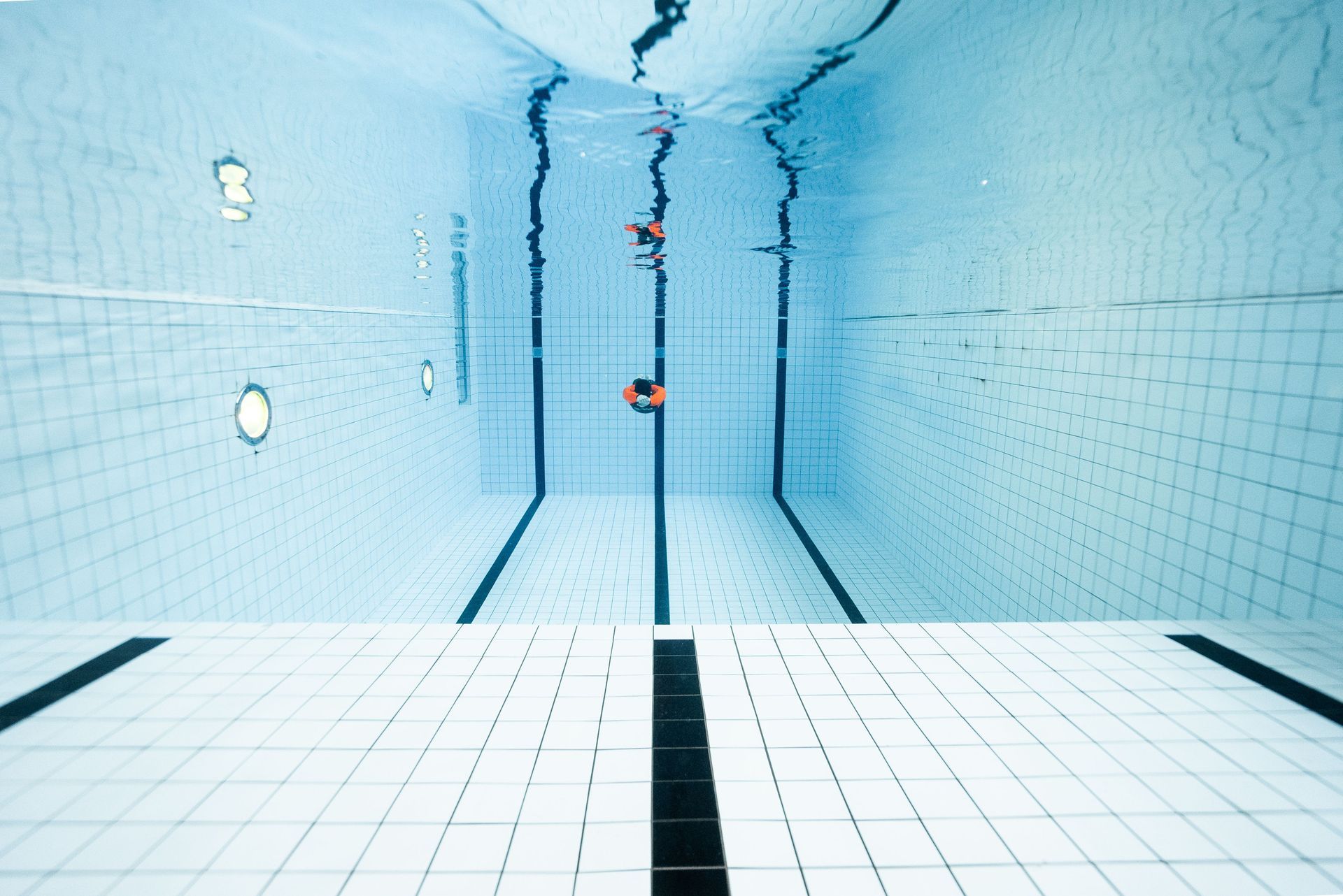 A person is swimming underwater in a swimming pool.