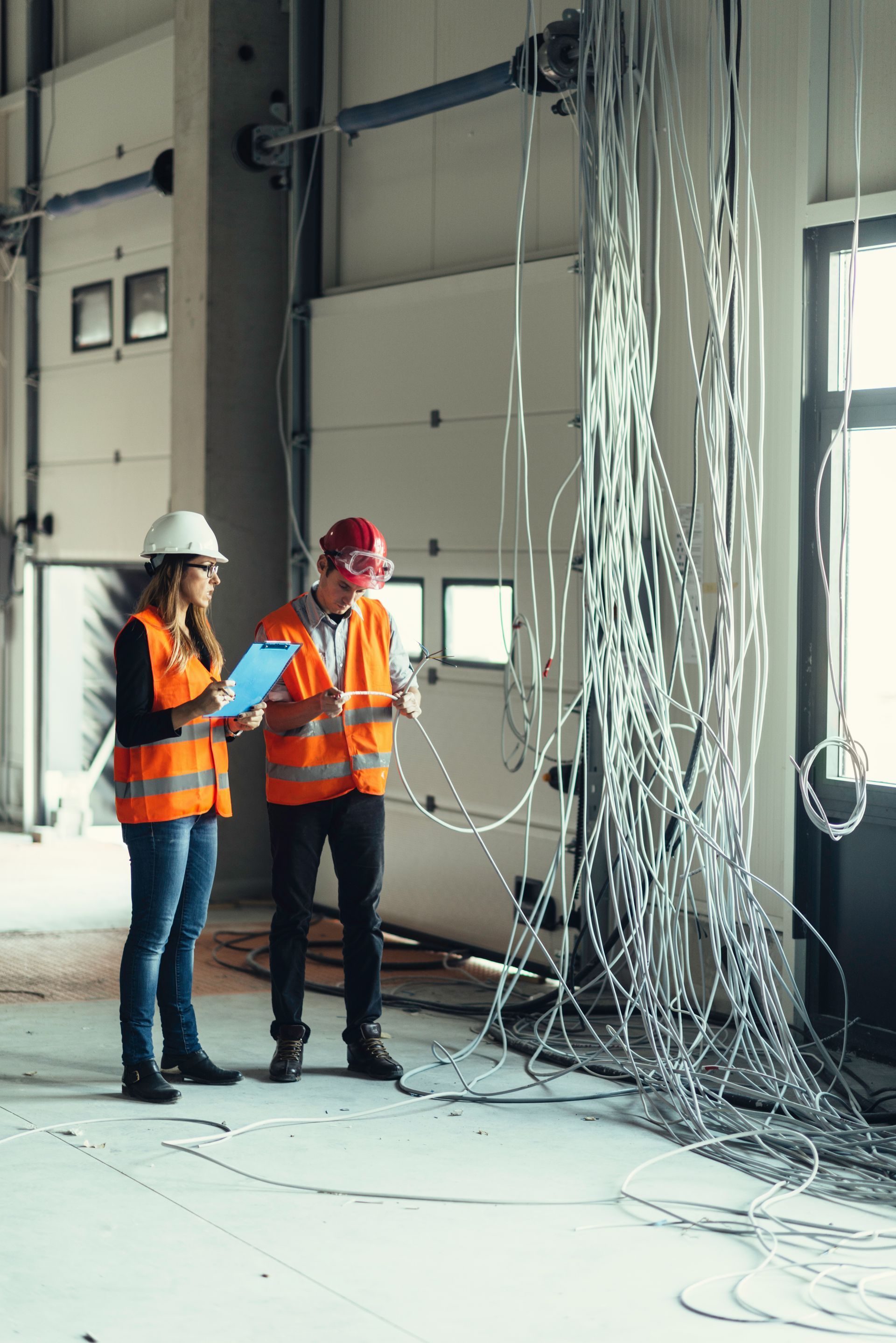 A man and a woman are standing in a building looking at a clipboard.