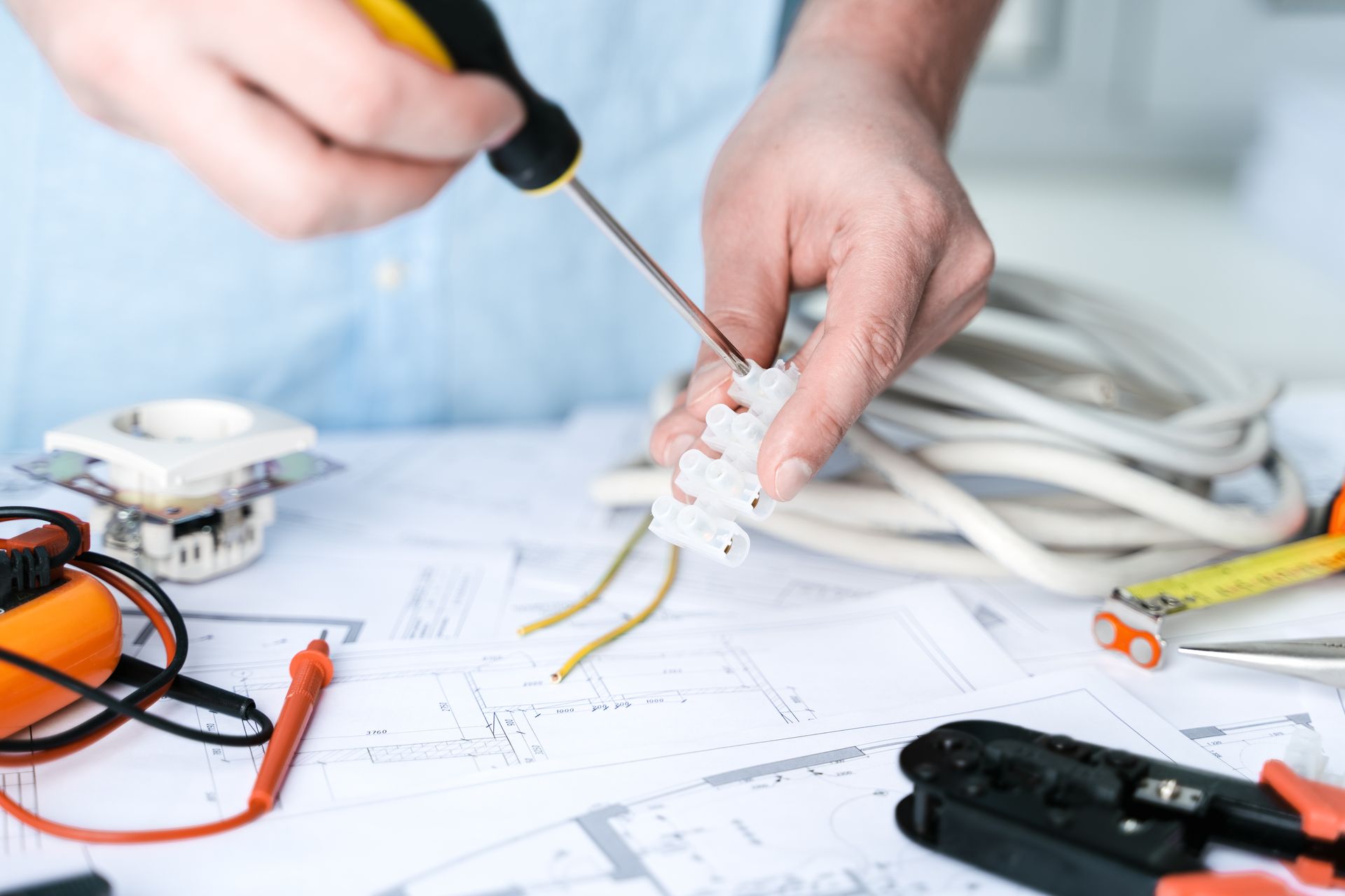 A man is working on electrical wires with a screwdriver.