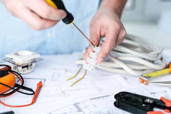 A man is working on electrical wires with a screwdriver.