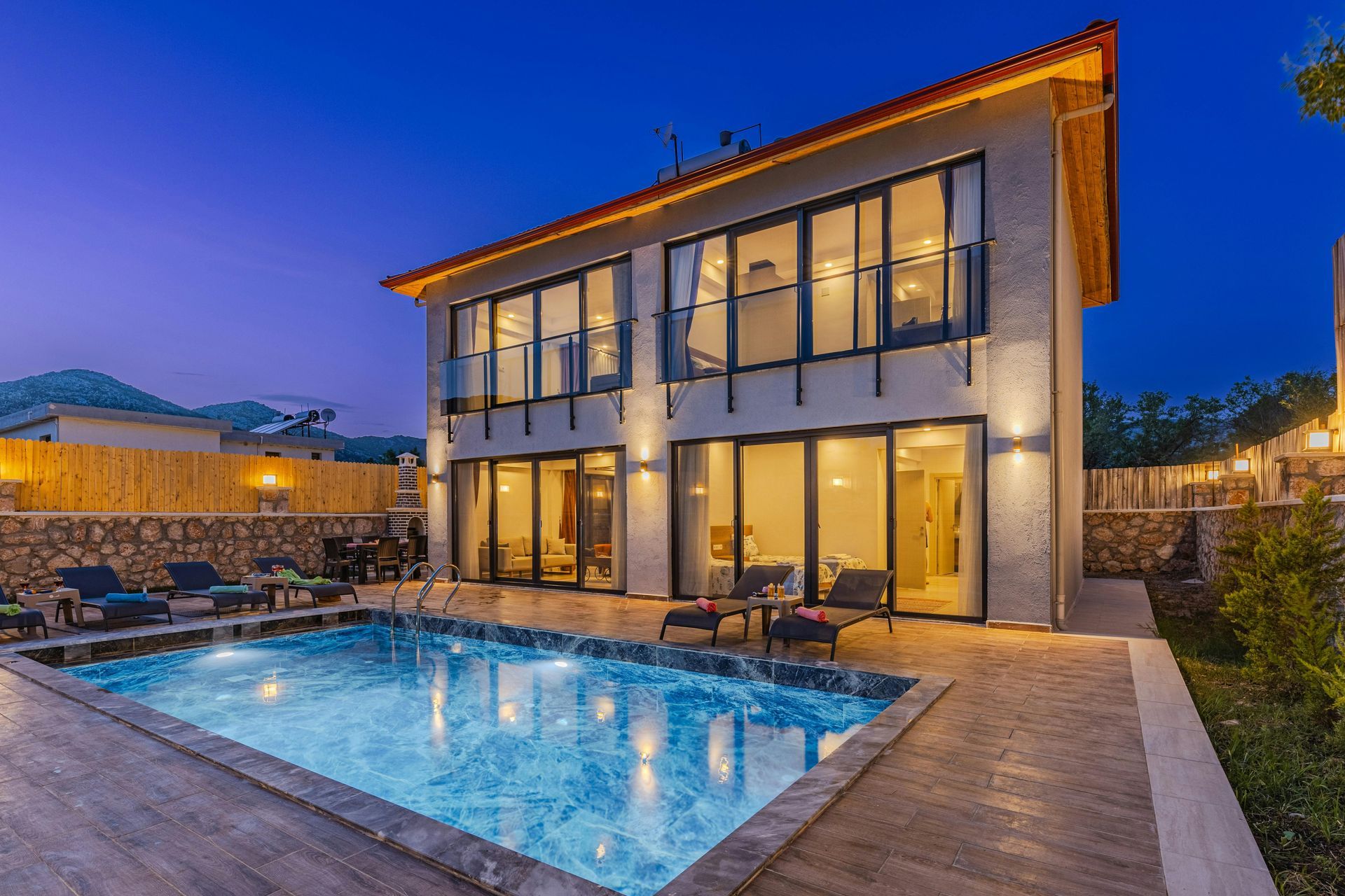Modern home with illuminated pool and outdoor lighting at dusk