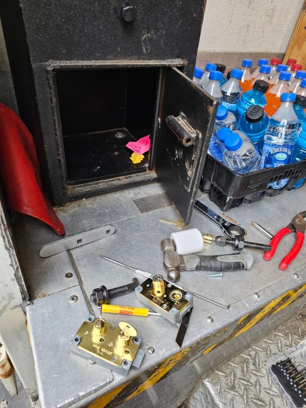 A bunch of bottles of water are sitting on a table next to a safe.