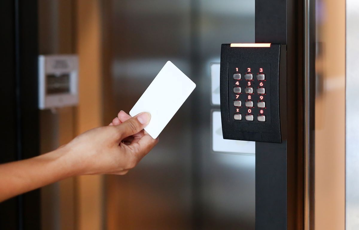 A person is holding a card in front of a keypad.