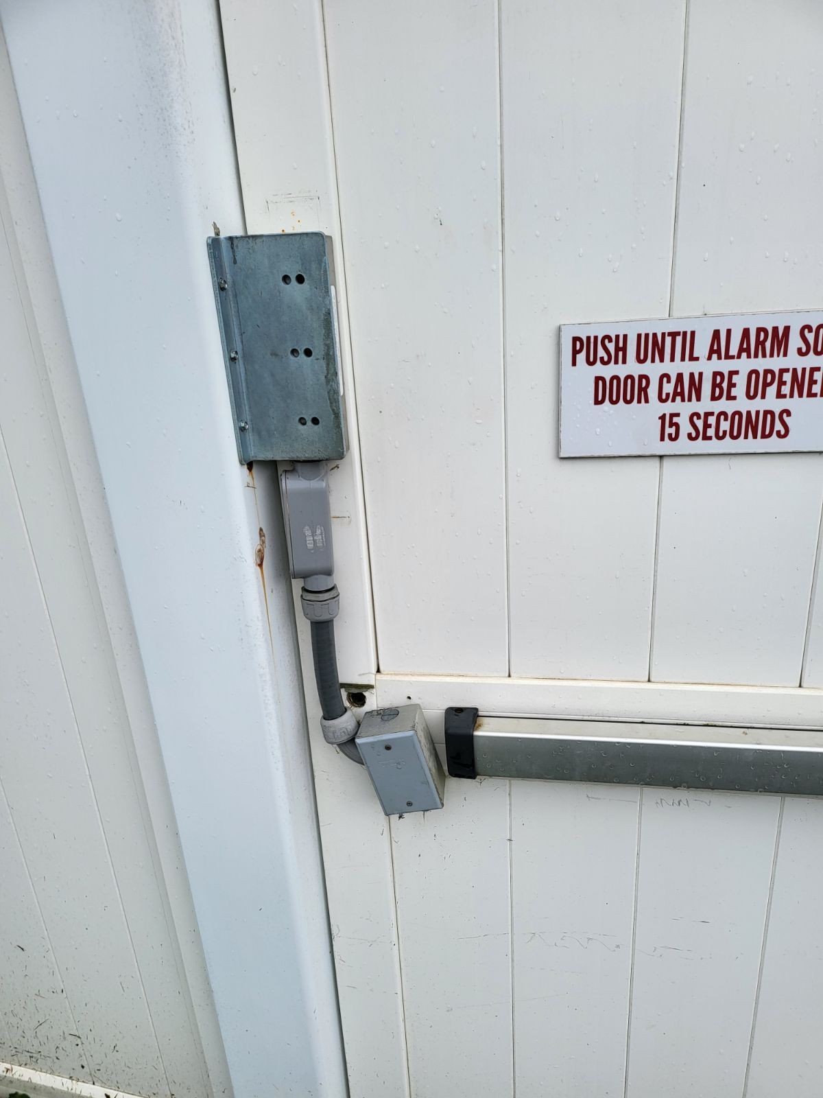 A white door with a sign on it that says `` push until alarm sound door can be opened 15 seconds ''.