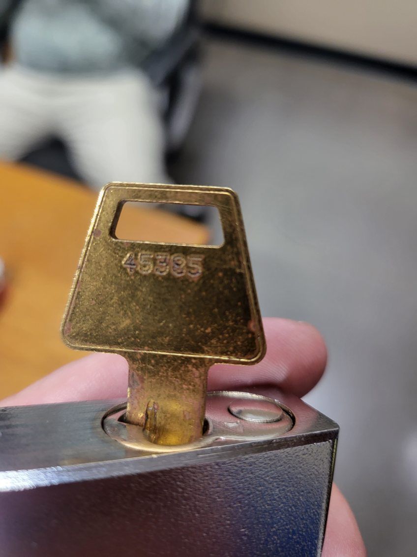 A person is holding a padlock with a key in it.