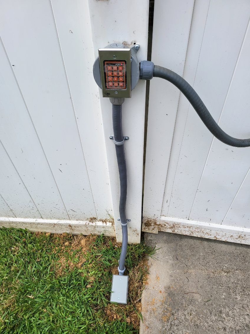 A keypad is attached to the side of a white fence.