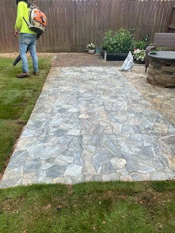 A man is walking down a stone walkway with a backpack.