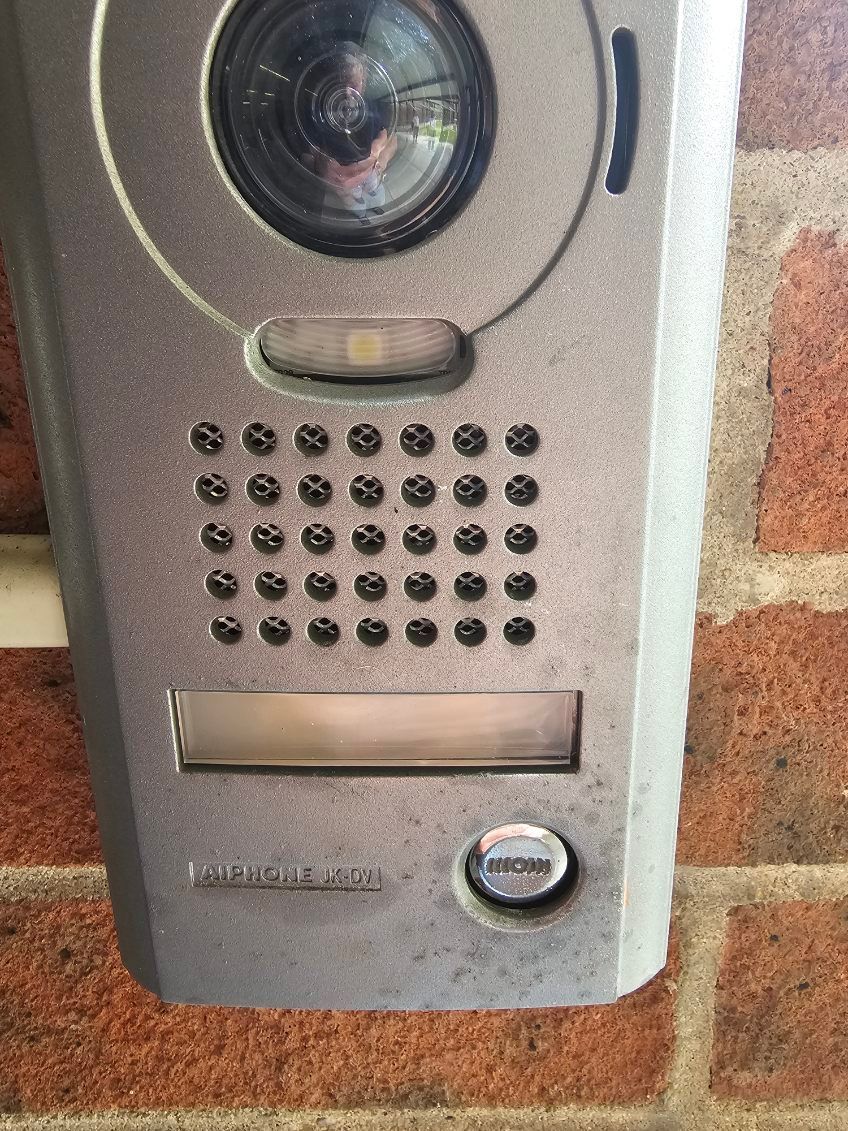 A doorbell is hanging on a brick wall.