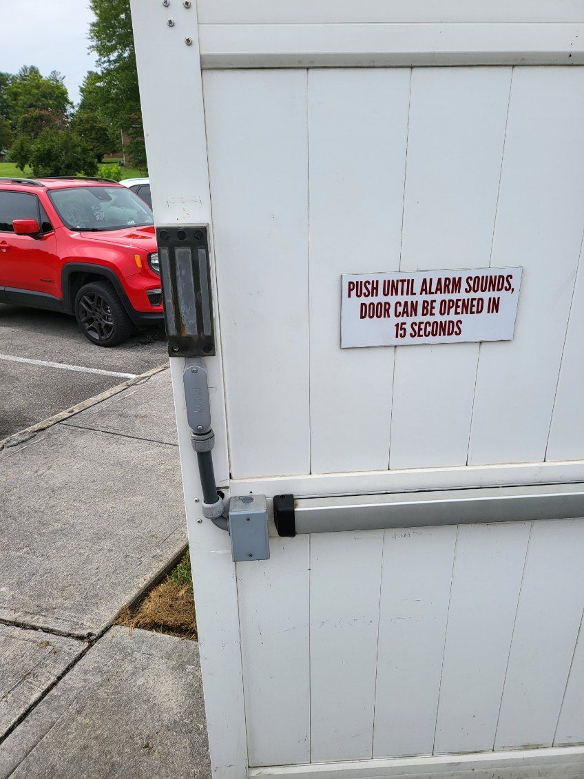 A red jeep is parked in a parking lot next to a white gate.