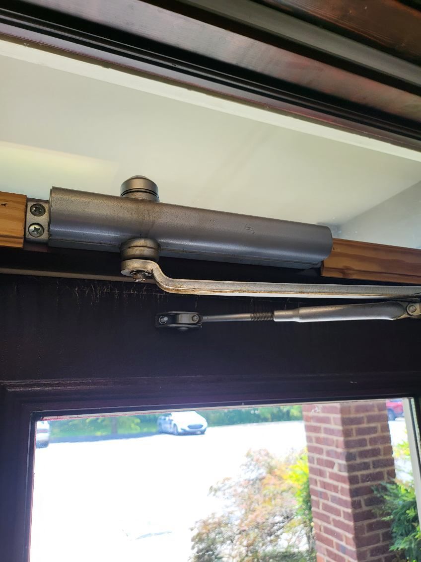 A close up of a door closer on a door.