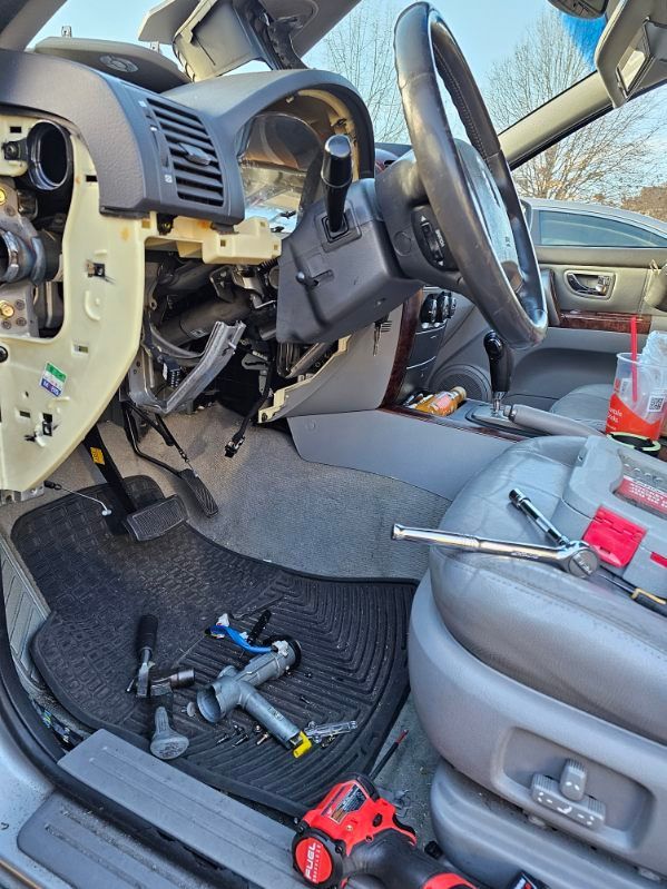 The inside of a car with the steering wheel removed and tools on the floor.